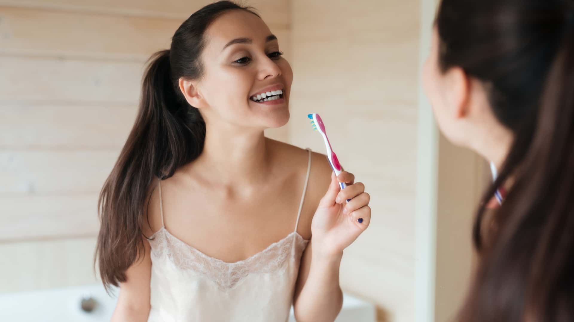 woman_brushing_teeth Woman brushing teeth in mirror